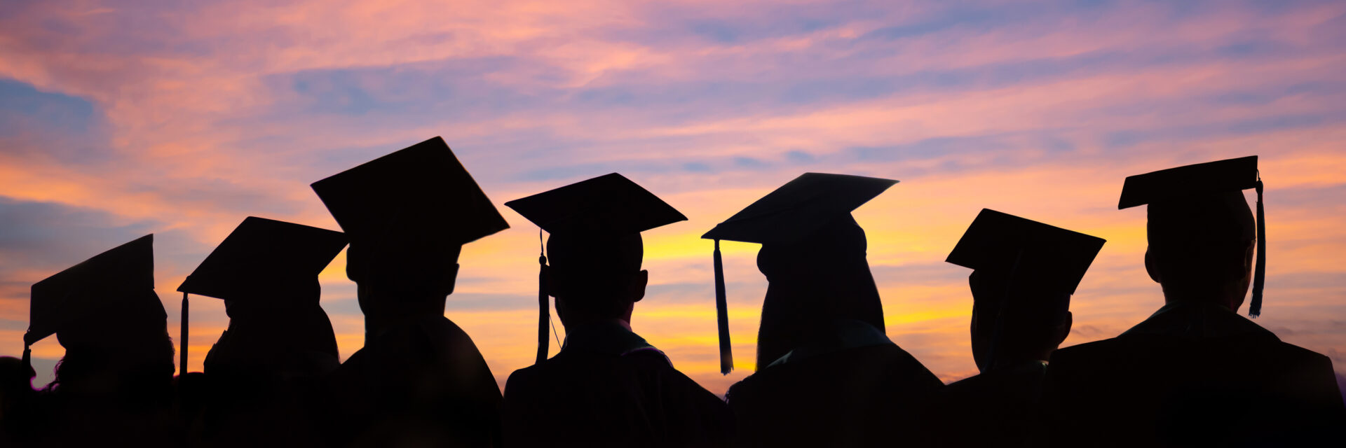 Silhouettes of students with graduate caps in a row on sunset background. Graduation ceremony at university web banner.